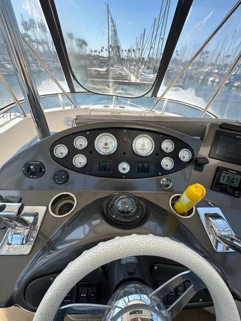 Slide: The Image of 2003 Riviera 37 Flybridge helm with gauges and marina view. - 5