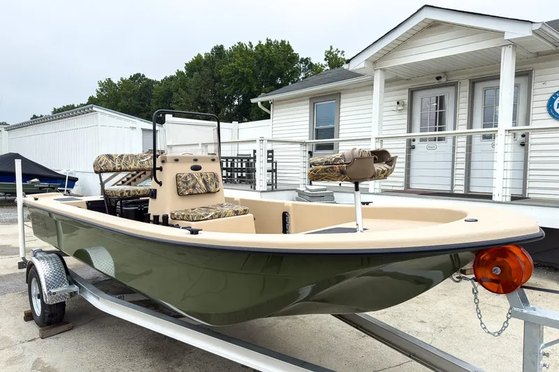 The Image of 2026 Carolina Skiff E20 JVX CC Sportsman boat on trailer, parked near white building. - 0