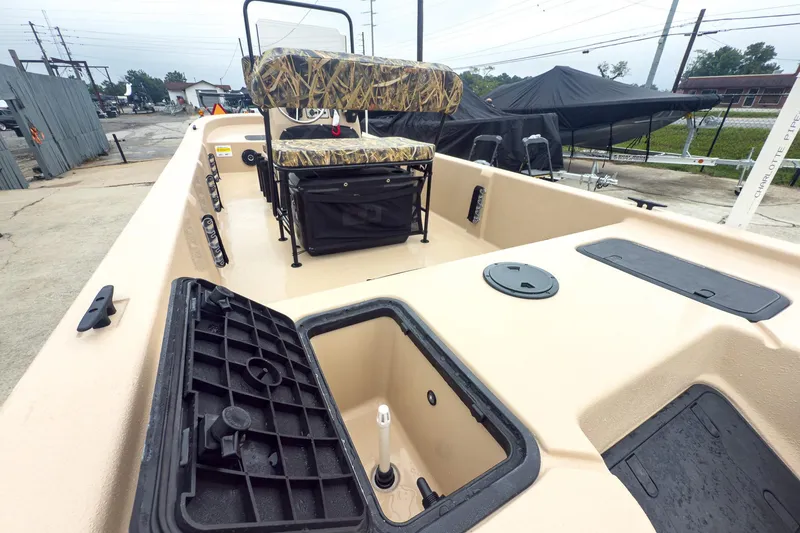 Slide: The Image of 2026 Carolina Skiff E20 JVX CC Sportsman boat interior with storage compartments and camo seating. - 14