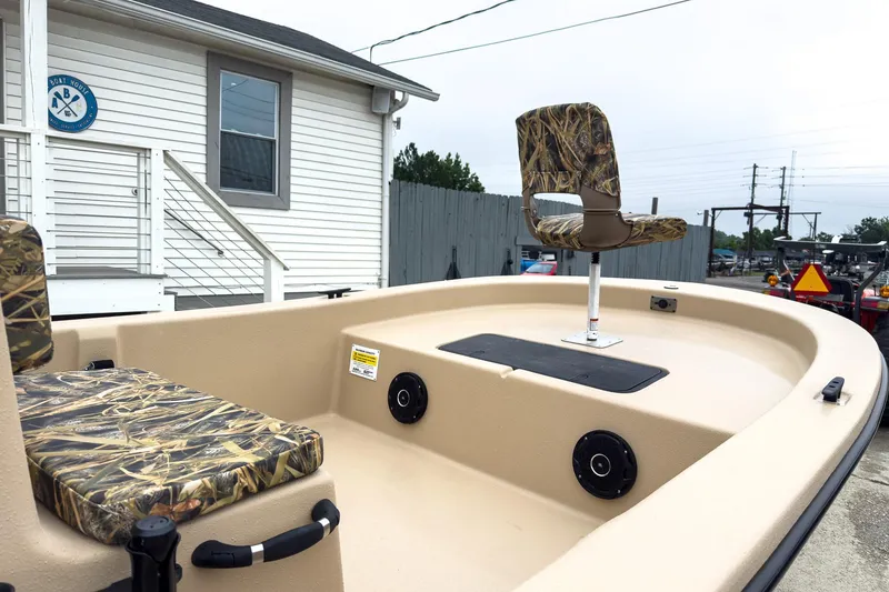 Slide: The Image of 2026 Carolina Skiff E20 JVX CC Sportsman boat with camo seats, docked near a building. - 17
