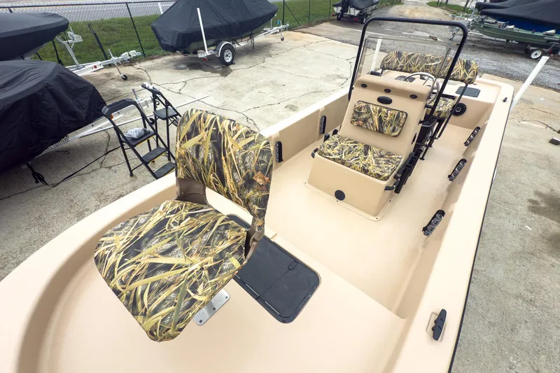 Slide: The Image of 2026 Carolina Skiff E20 JVX CC Sportsman boat with camouflage seating, parked outdoors. - 22