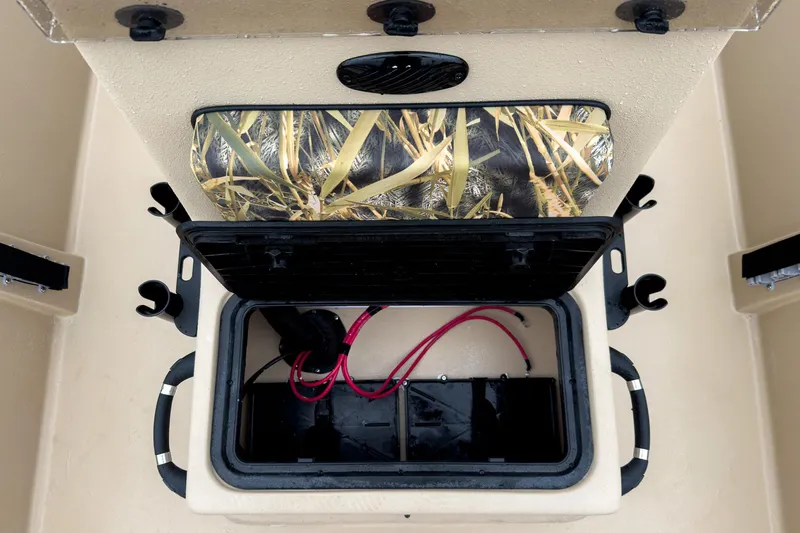 Slide: The Image of 2026 Carolina Skiff E20 JVX CC Sportsman boat storage compartment with camo lid and wiring. - 24