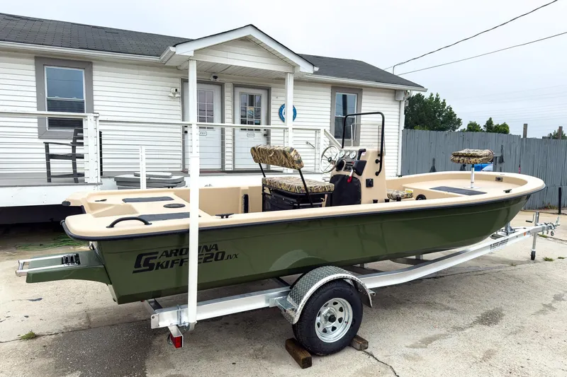 Slide: The Image of 2026 Carolina Skiff E20 JVX CC Sportsman boat on trailer, parked outside a house. - 25