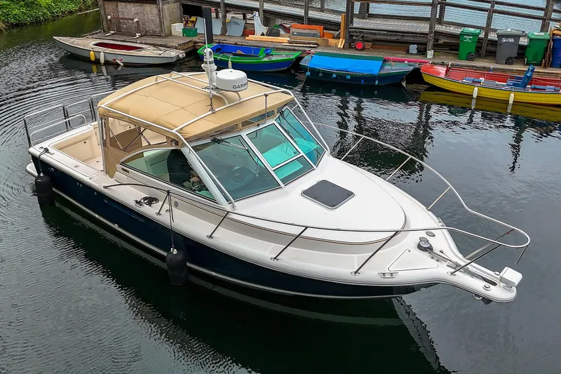 Slide: The Image of 2006 Tiara Yachts 2900 Coronet docked in a marina, surrounded by colorful boats. - 7