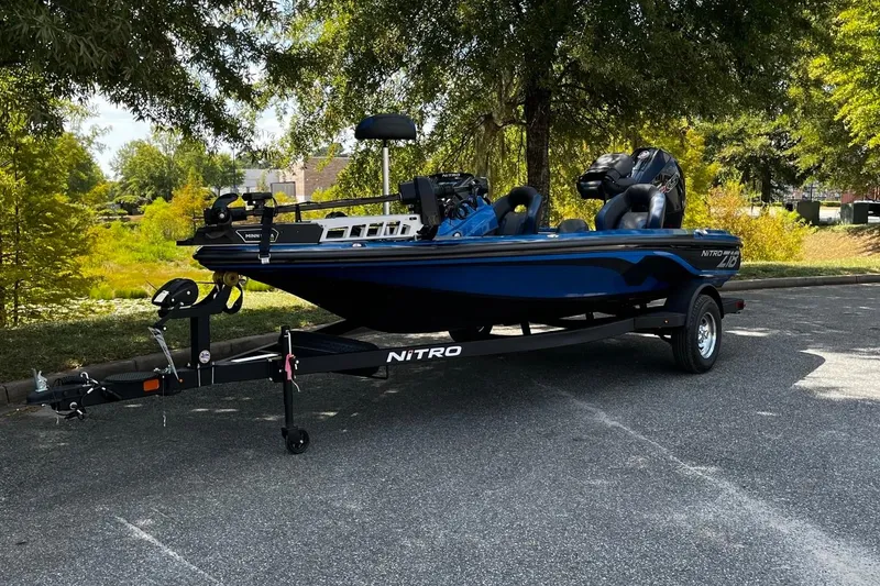 The Image of 2025 Nitro Z18 boat on trailer, parked outdoors under trees. - 1