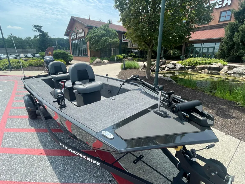 Slide: The Image of 2025 Tracker Panfish 17 boat parked outdoors near a landscaped area. - 2