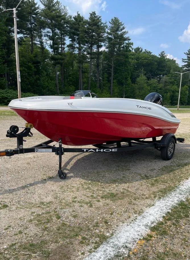 Slide: The Image of 2025 Tahoe T16 boat with red hull on a trailer, parked outdoors. - 2