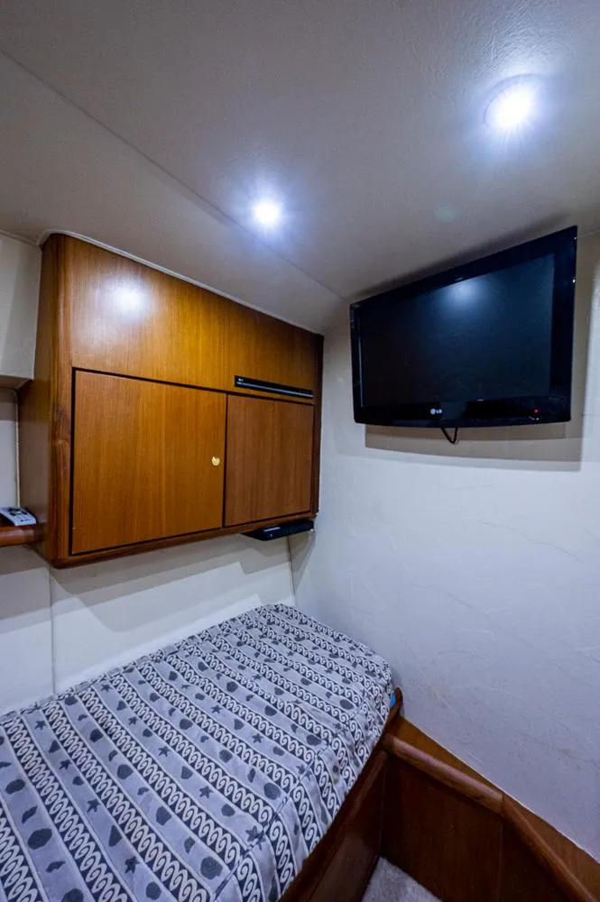 Slide: The Image of 1999 Ocean Yachts 60 Convertible cabin with bed, TV, and wooden storage. - 37