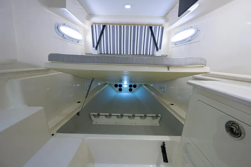 Slide: The Image of 2022 Cobia 350 Center Console cabin interior with bed, storage, and portholes. - 29