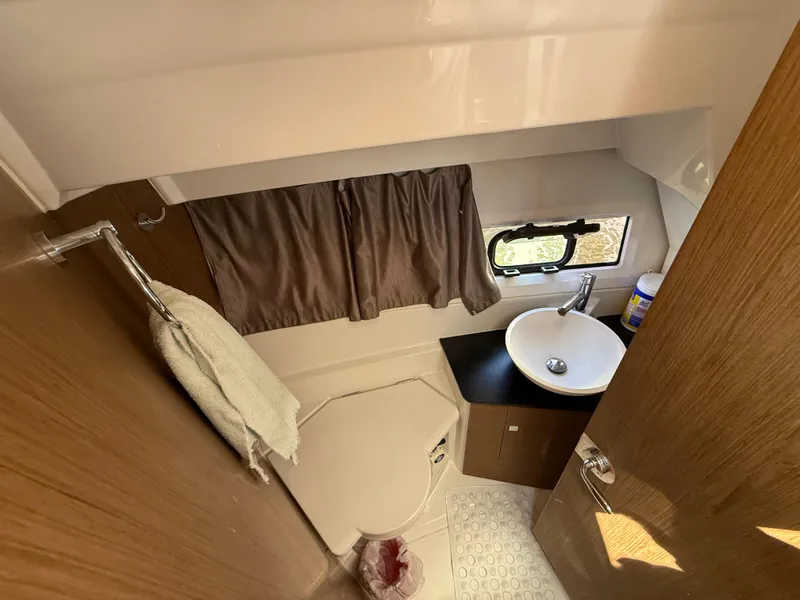 Slide: The Image of Compact bathroom in 2018 Jeanneau NC 895 boat with sink, toilet, and window. - 11