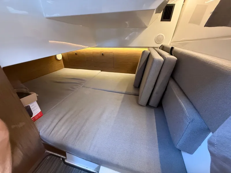 Slide: The Image of 2018 Jeanneau NC 895 interior cabin with gray cushions and wooden accents. - 12