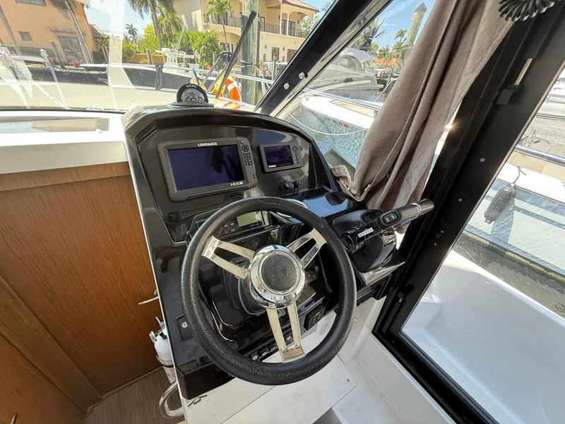 Slide: The Image of 2018 Jeanneau NC 895 helm with steering wheel and navigation controls. - 15