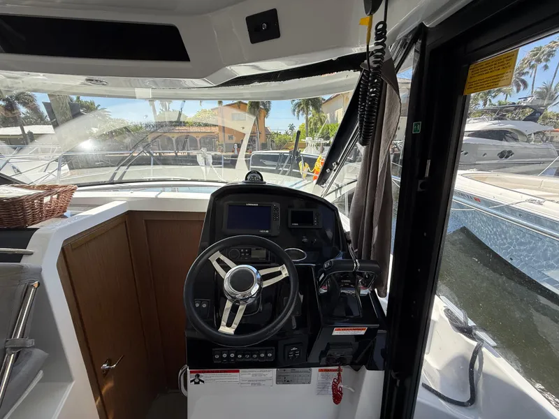 Slide: The Image of 2018 Jeanneau NC 895 helm with steering wheel and navigation controls. - 16
