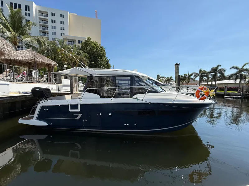 Slide: The Image of 2018 Jeanneau NC 895 boat docked in a marina with palm trees and buildings. - 2