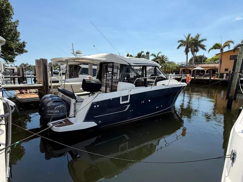 Slide: The Image of 2018 Jeanneau NC 895 boat docked in a sunny marina with palm trees. - 4