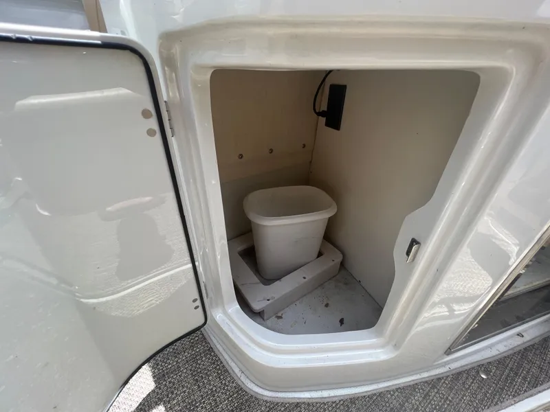 Slide: The Image of Storage compartment in 2017 Crownline 294 CR boat with a small trash bin inside. - 21