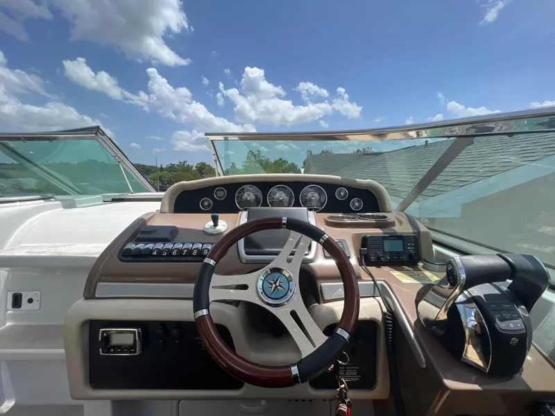 Slide: The Image of 2017 Crownline 294 CR boat dashboard with steering wheel and controls under blue sky. - 23
