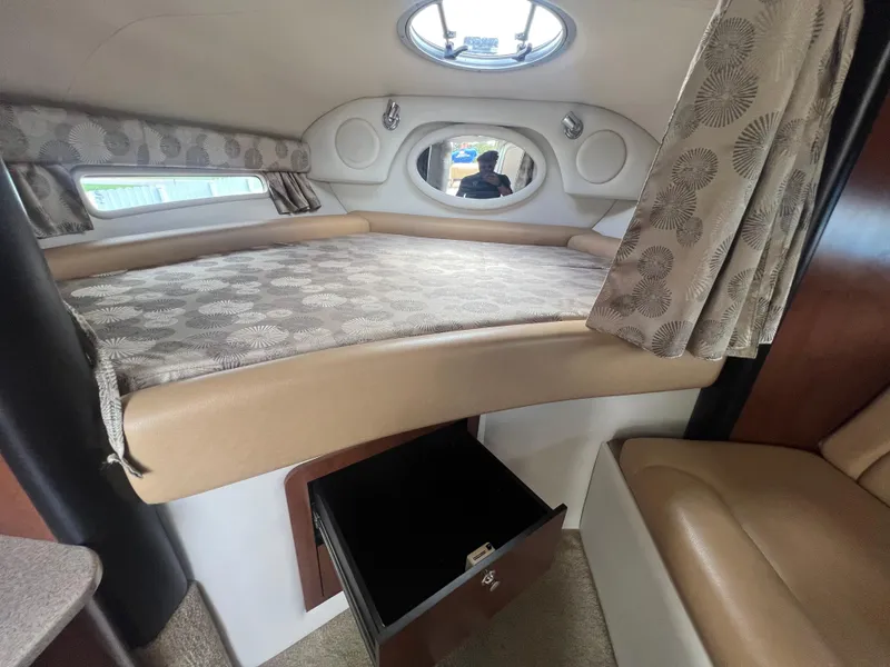 Slide: The Image of 2017 Crownline 294 CR cabin interior with bed, storage, and porthole window. - 34