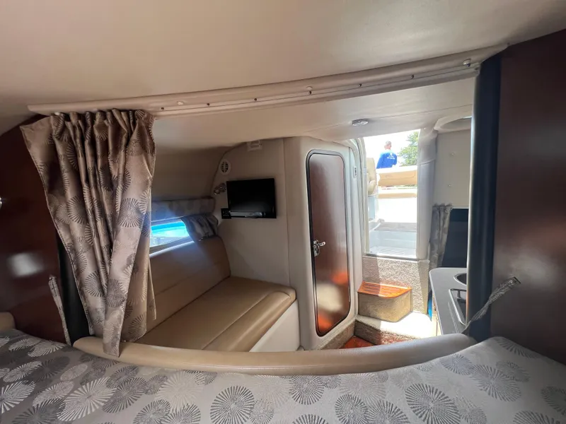 Slide: The Image of 2017 Crownline 294 CR cabin interior with seating, TV, and patterned curtains. - 38