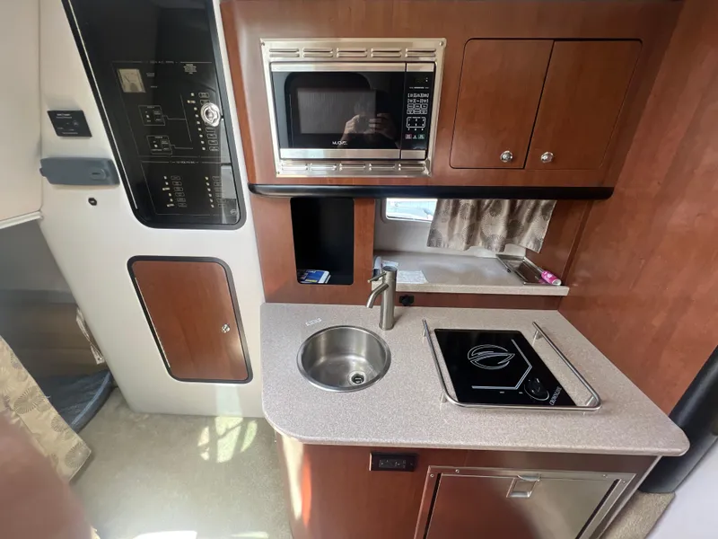 Slide: The Image of 2017 Crownline 294 CR boat kitchen with microwave, sink, and stove. - 44