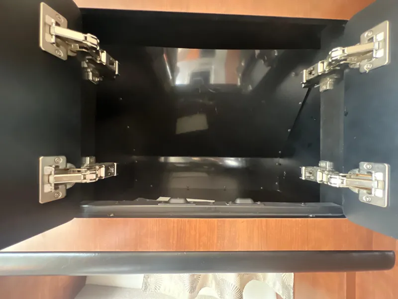 Slide: The Image of Open cabinet with metal hinges inside a 2017 Crownline 294 CR boat. - 49
