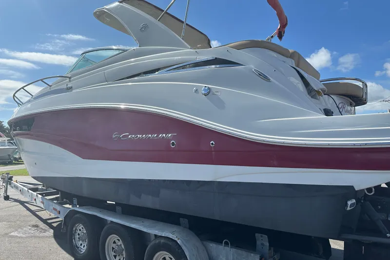 Slide: The Image of 2017 Crownline 294 CR boat on trailer, white and red exterior, under blue sky. - 6