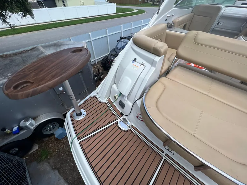 Slide: The Image of 2017 Crownline 294 CR boat interior with tan seating and wooden table. - 77