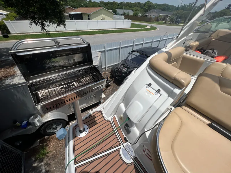 Slide: The Image of 2017 Crownline 294 CR boat with tan seating, docked near a large outdoor grill. - 79