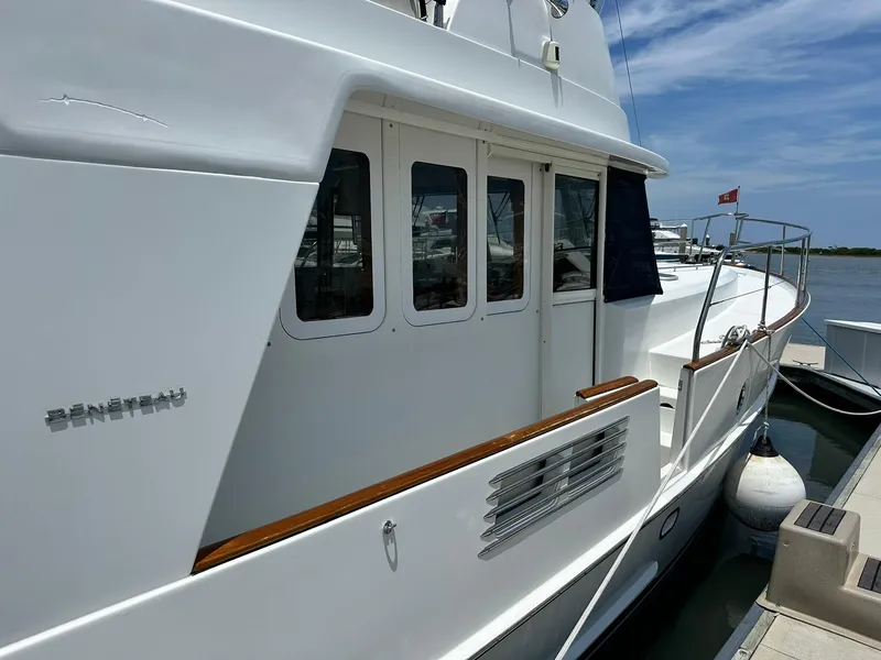Slide: The Image of 2005 Beneteau Swift Trawler 42 docked, showcasing sleek white exterior and windows. - 11