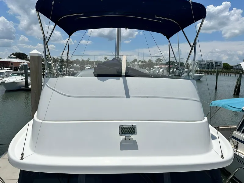 Slide: The Image of 2005 Beneteau Swift Trawler 42 with blue canopy, docked at marina under clear sky. - 20
