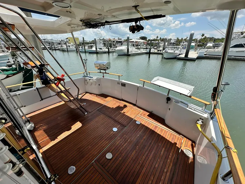 Slide: The Image of 2005 Beneteau Swift Trawler 42 with wooden deck, docked at marina under clear skies. - 26