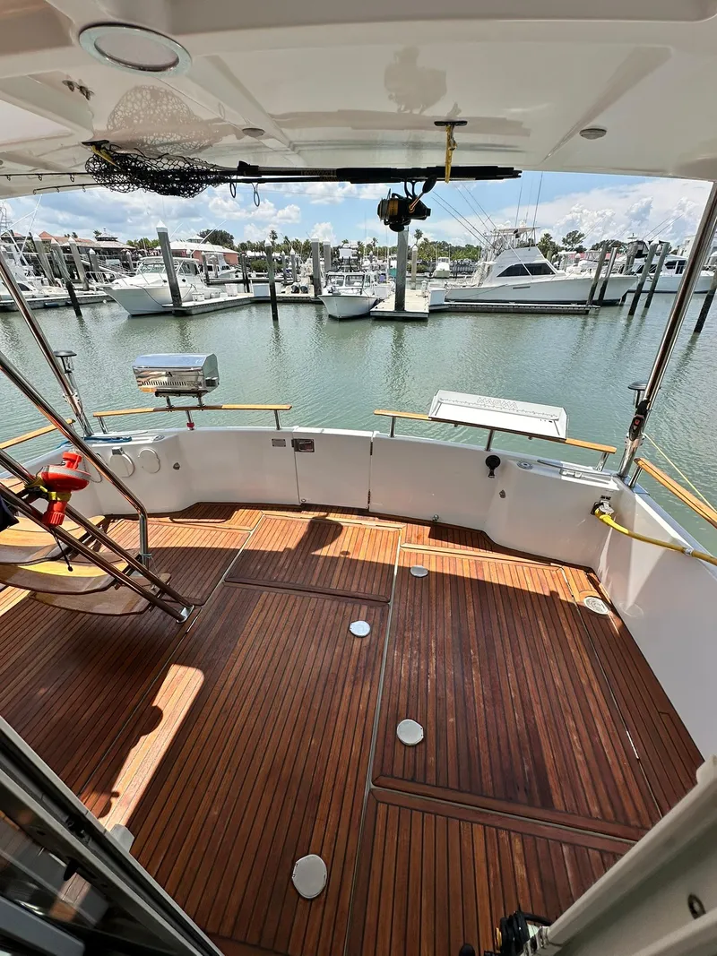 Slide: The Image of 2005 Beneteau Swift Trawler 42 with wooden deck, docked at marina with boats in background. - 28
