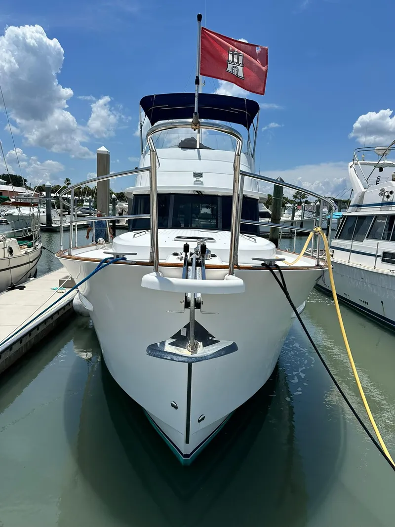 Slide: The Image of 2005 Beneteau Swift Trawler 42 docked, front view with flag, under blue sky. - 3