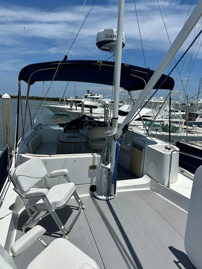 Slide: The Image of 2005 Beneteau Swift Trawler 42 docked, featuring spacious deck and seating under blue canopy. - 42