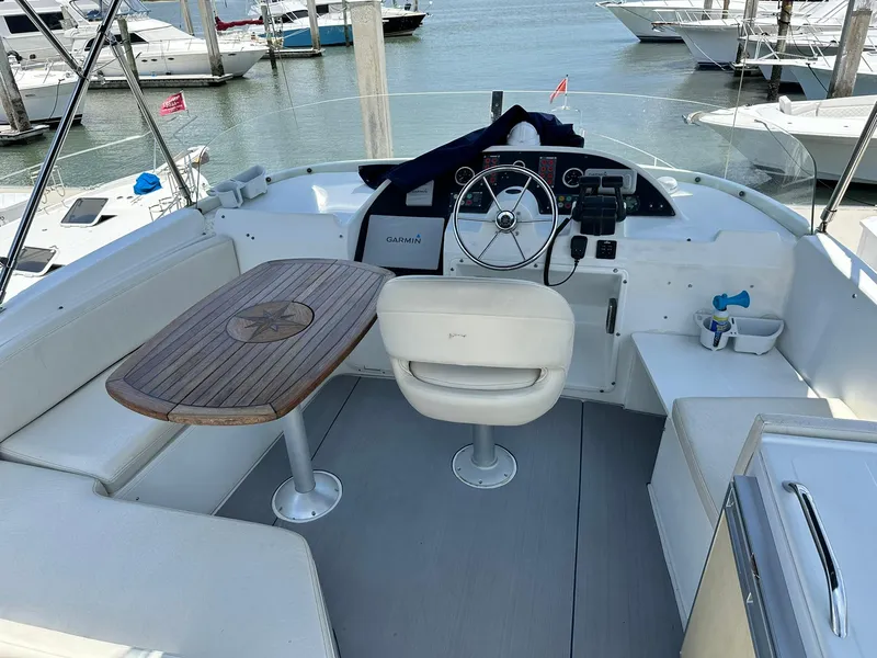 Slide: The Image of 2005 Beneteau Swift Trawler 42 cockpit with steering wheel, seating, and wooden table. - 44