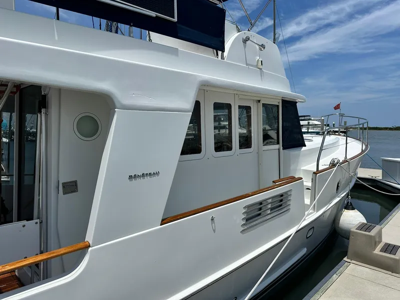 Slide: The Image of 2005 Beneteau Swift Trawler 42 docked, showcasing sleek white exterior and wooden accents. - 8