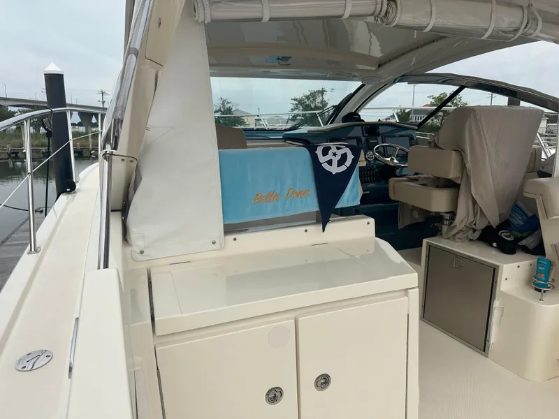 Slide: The Image of 2014 Pursuit SC 365i Sport Coupe interior with seating and helm, docked at marina. - 10