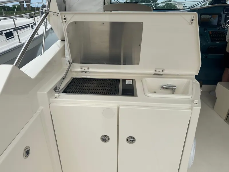 Slide: The Image of 2014 Pursuit SC 365i Sport Coupe boat interior with grill and sink setup. - 13