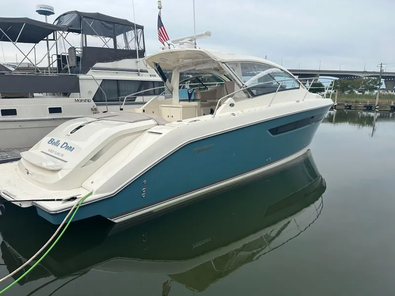 Slide: The Image of 2014 Pursuit SC 365i Sport Coupe docked in marina, sleek design, blue and white exterior. - 2