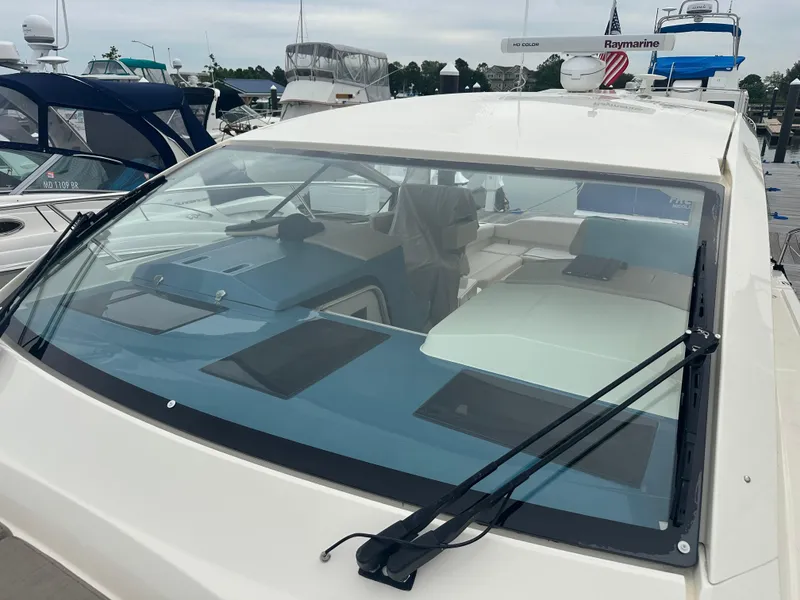 Slide: The Image of 2014 Pursuit SC 365i Sport Coupe at marina, showcasing sleek windshield design. - 23