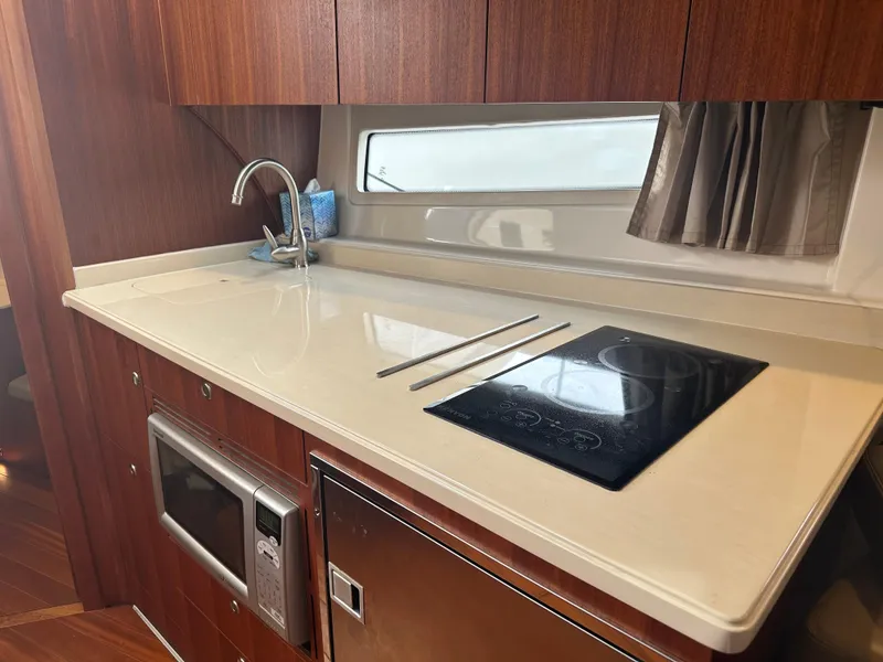Slide: The Image of 2014 Pursuit SC 365i Sport Coupe kitchen with stove, sink, microwave, and window. - 37