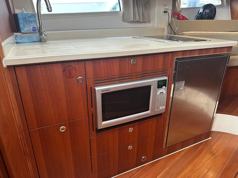 Slide: The Image of 2014 Pursuit SC 365i Sport Coupe kitchen with microwave, fridge, and wooden cabinetry. - 38