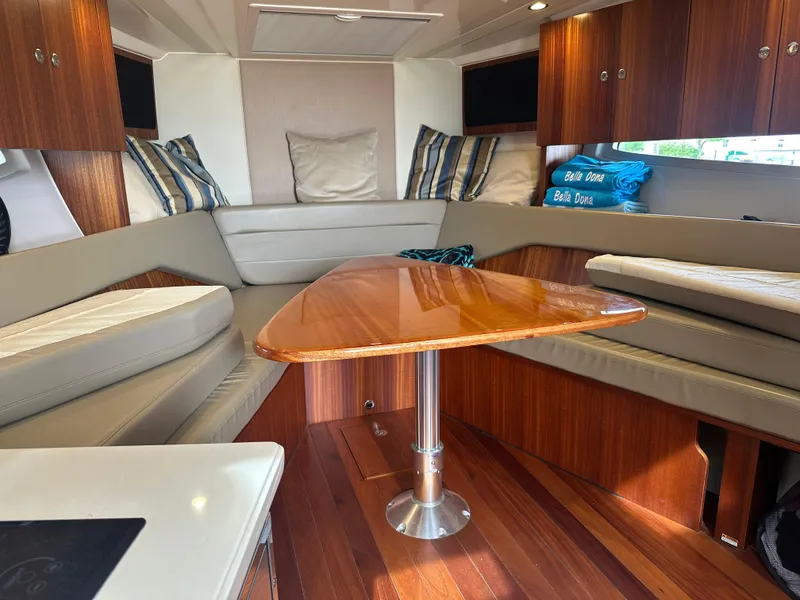 Slide: The Image of 2014 Pursuit SC 365i Sport Coupe interior with wood table, cushioned seating, and striped pillows. - 41