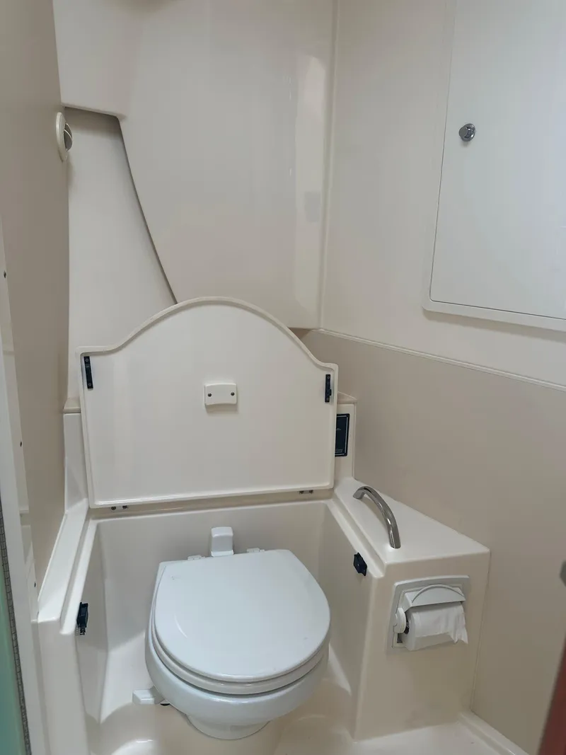Slide: The Image of 2014 Pursuit SC 365i Sport Coupe bathroom with white marine toilet and storage. - 44