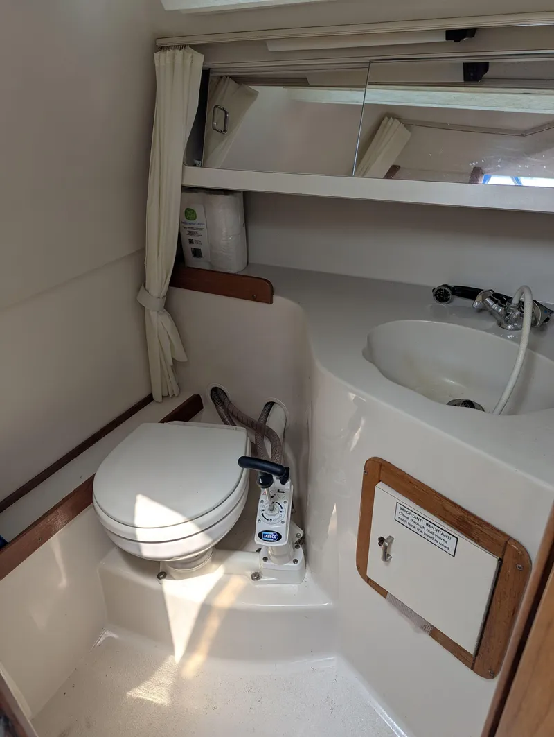 Slide: The Image of 1997 Catalina MkII boat bathroom with toilet, sink, mirror, and storage cabinet. - 11