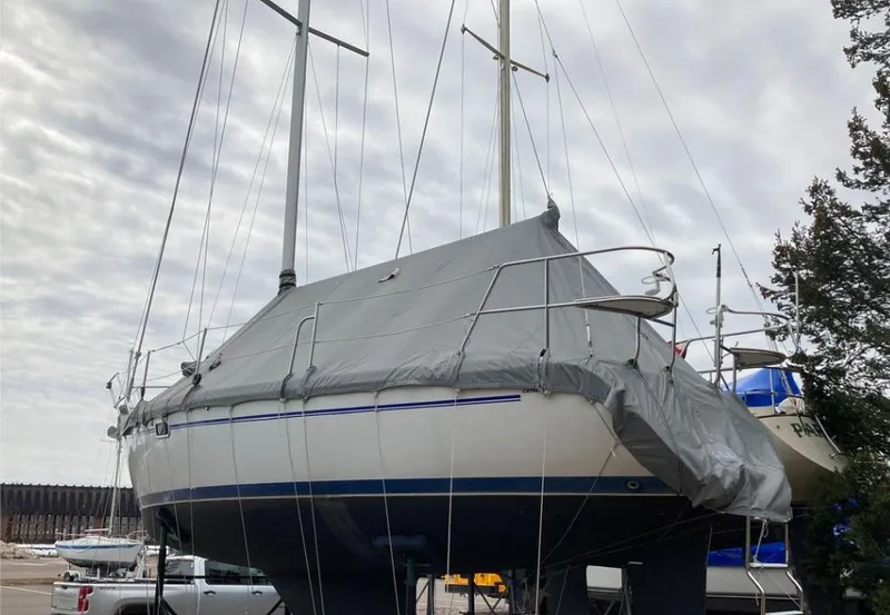 Slide: The Image of 1997 Catalina MkII sailboat covered and docked, with masts visible against a cloudy sky. - 14