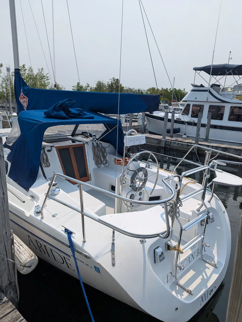Slide: The Image of 1997 Catalina MkII sailboat docked, featuring blue canvas cover and dual steering wheels. - 2