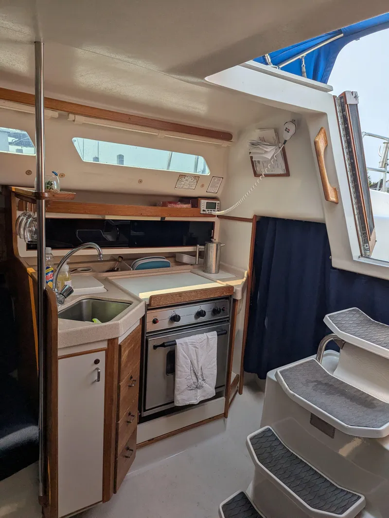 Slide: The Image of Interior of a 1997 Catalina MkII sailboat featuring a compact kitchen and staircase. - 7