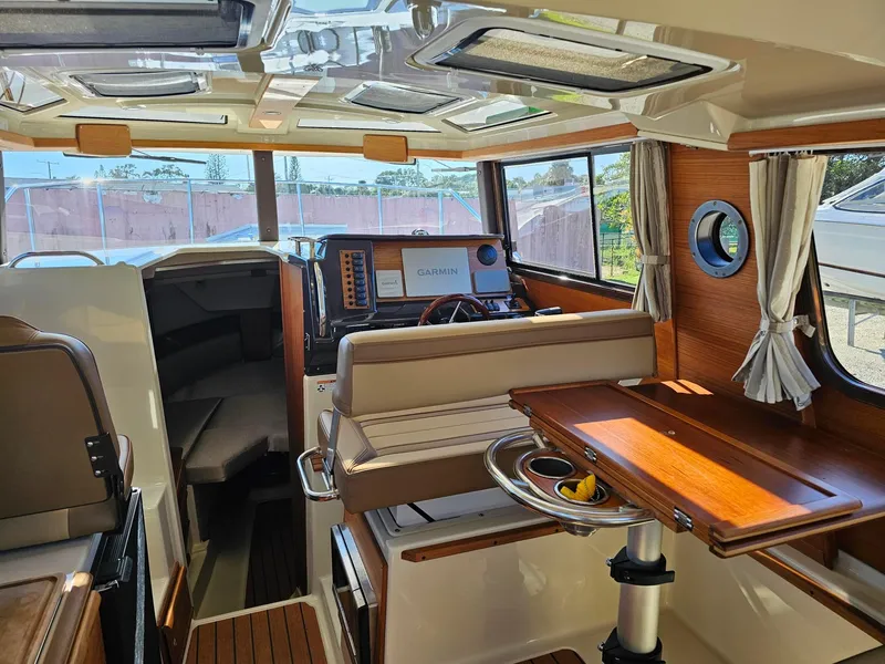 Slide: The Image of Interior of 2023 Ranger Tugs 27R boat, featuring seating, table, and navigation equipment. - 16