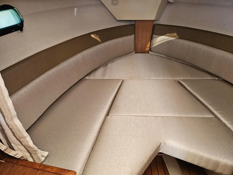 Slide: The Image of 2023 Ranger Tugs 27R interior cabin with cushioned seating and wood accents. - 19